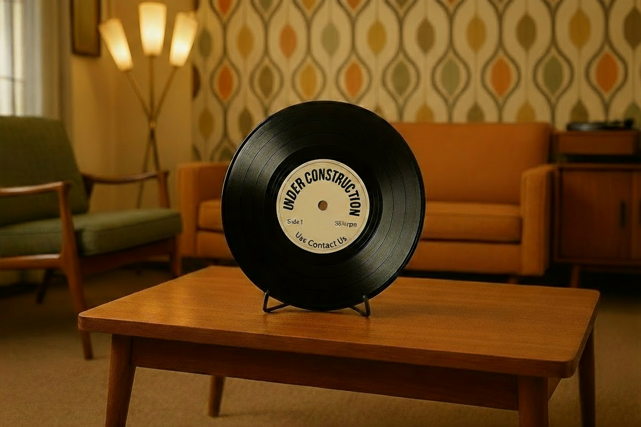1960's mcm room. looking at the corner of the room. in the middle of the coffee table is a physical record held in a stand.  On the label, Under Construction is printed at the top and both words follow the labels arch. across the label on the same line below the center hole of the record in printed Side 1 on the left side of the label and 33-1/3 rpm on the right side of the label.  At the bottom of the label, in smaller text is printed Use Contact Us.  All 3 words follow the labels arch 